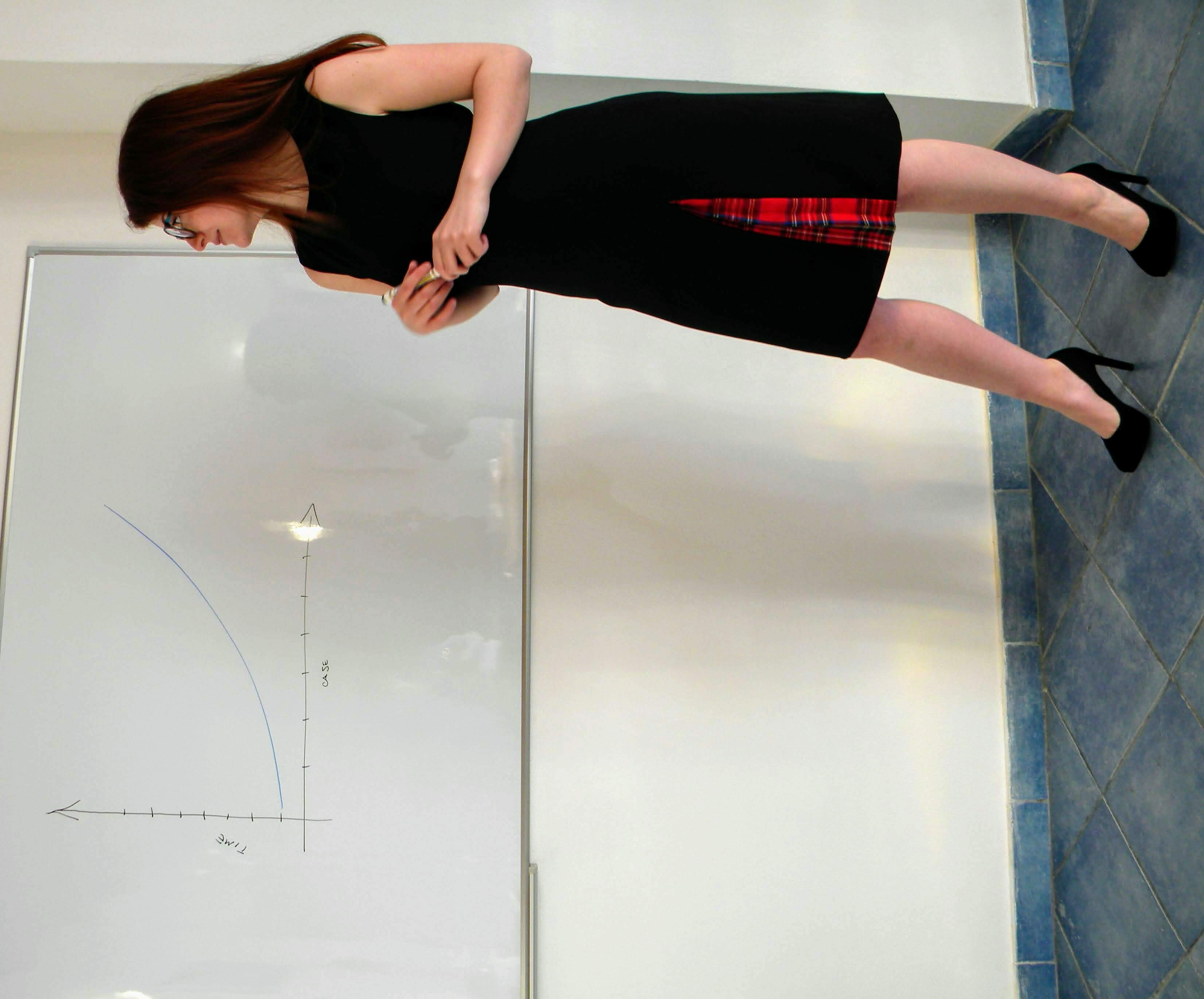 Ragazza vestita di nero che presenta un grafico alla lavagna.