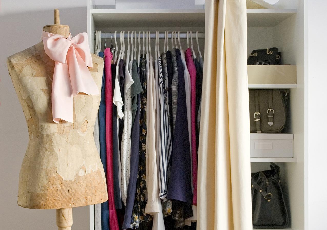 un piccolo armadio pieno di vestiti con davanti un manichino.